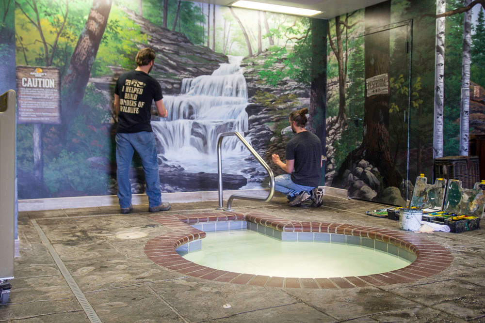 Brothers Adam, left, and Aaron Wolken paint a waterfall behind the hotel hot tub.