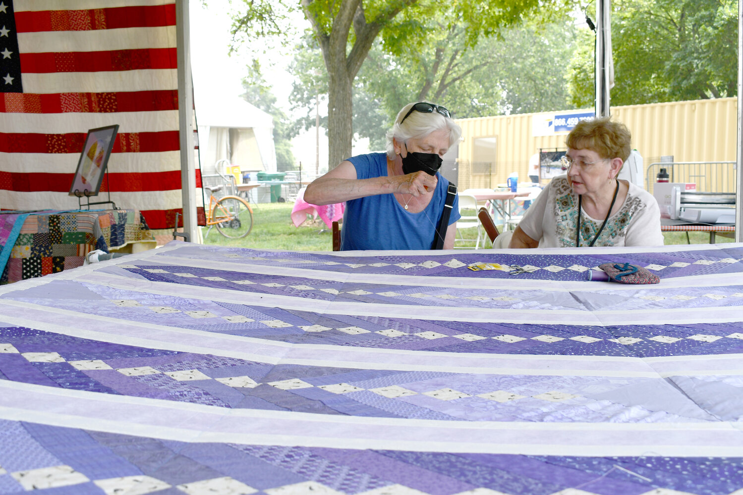 Visitors at the Folklife Festival can add stitches to a group quilt as they learn about Ozarks culture.